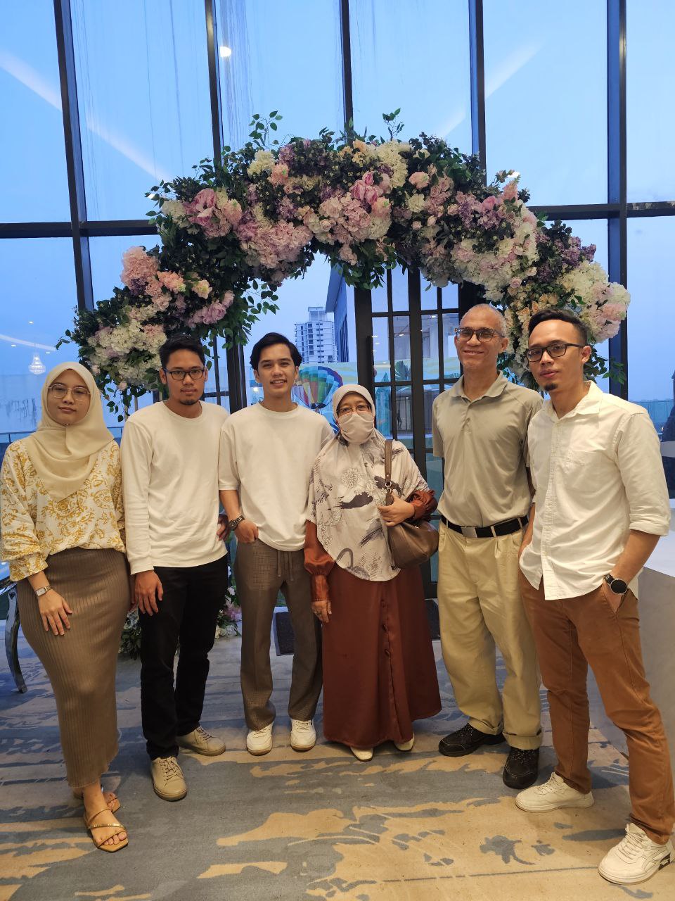 Family portrait in front of a floral arch at a celebration
